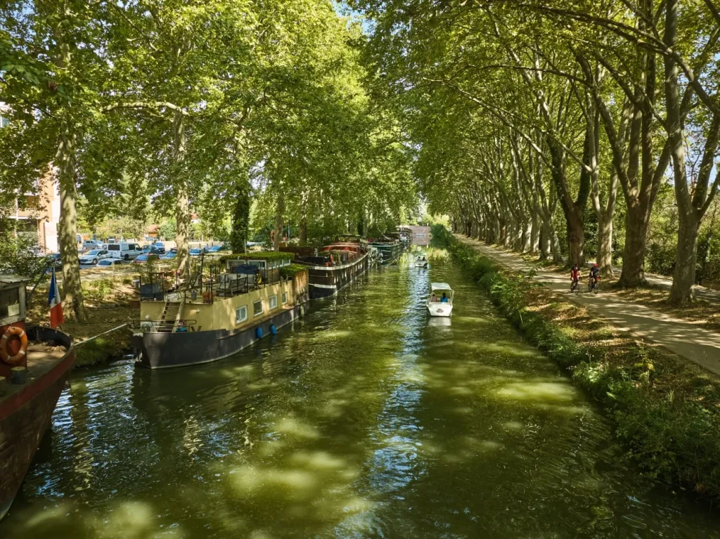 balade-bateau-electrique-canal-du-midi-toulouse-peniches Bateau électrique sans permis naviguant sur le Canal du Midi, entre les péniches amarrées et le chemin de halage